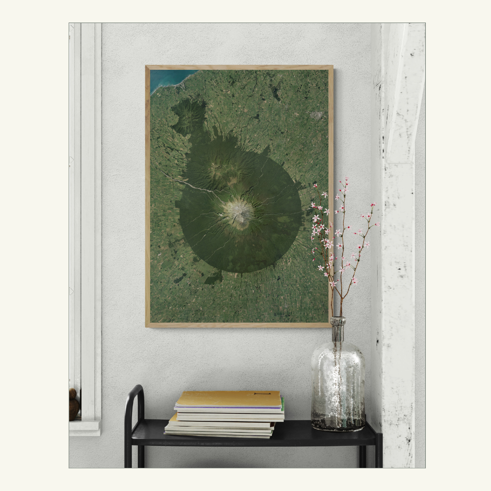 Framed print of Taranaki on a wall with a vase and books below