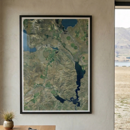 Framed landscape print of a farm on a wall with a desk and window view in the foreground