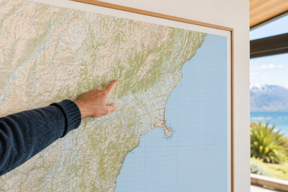 Person pointing at a map of Kaikoura with a scenic view outside.