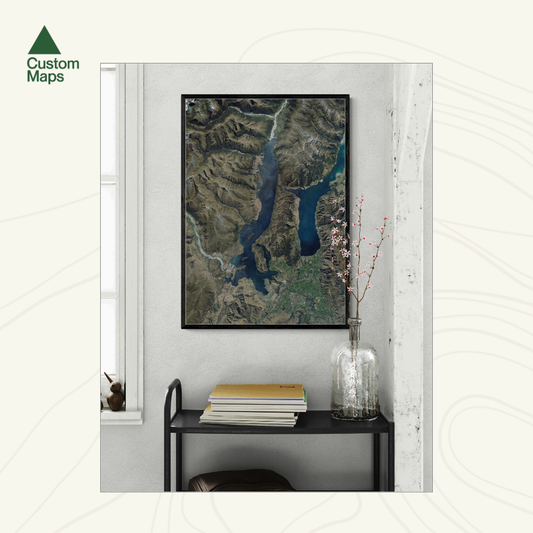 Framed aerial art print of Lake Wanaka on a wall in a room with a shelf and vase.