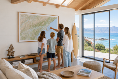 Family in a modern living room with a large map of Kaikoura on the wall, looking out at a scenic view.