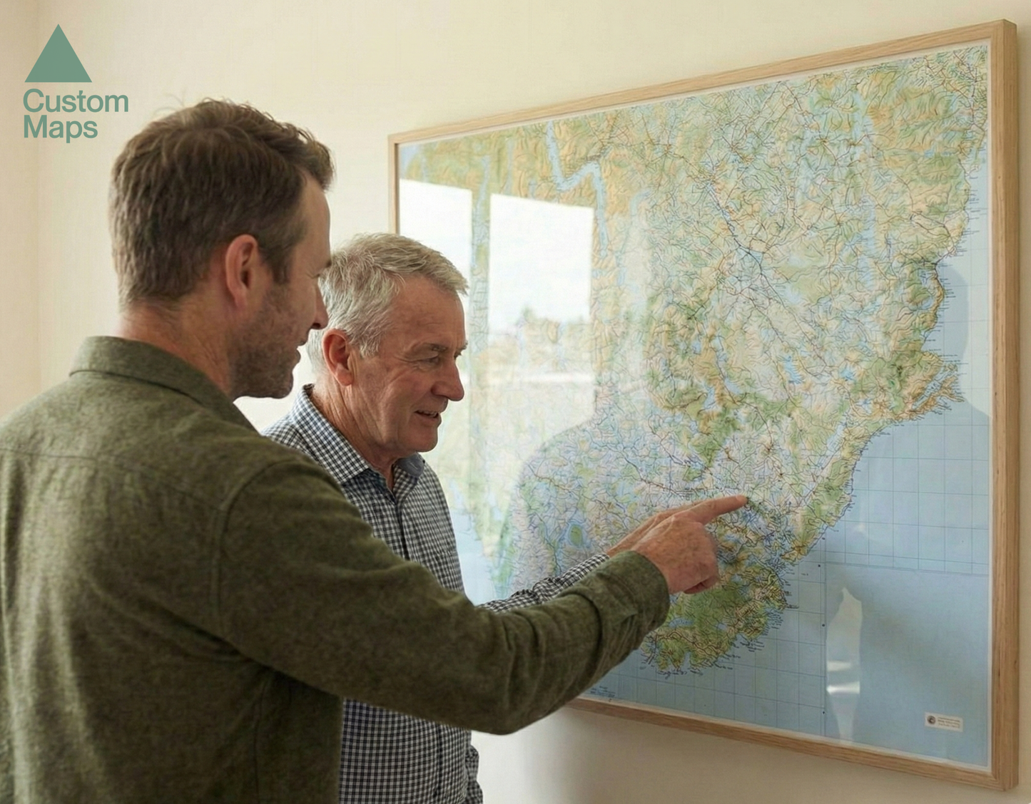Two men looking at a map on a wall, with 'Custom Maps' branding.