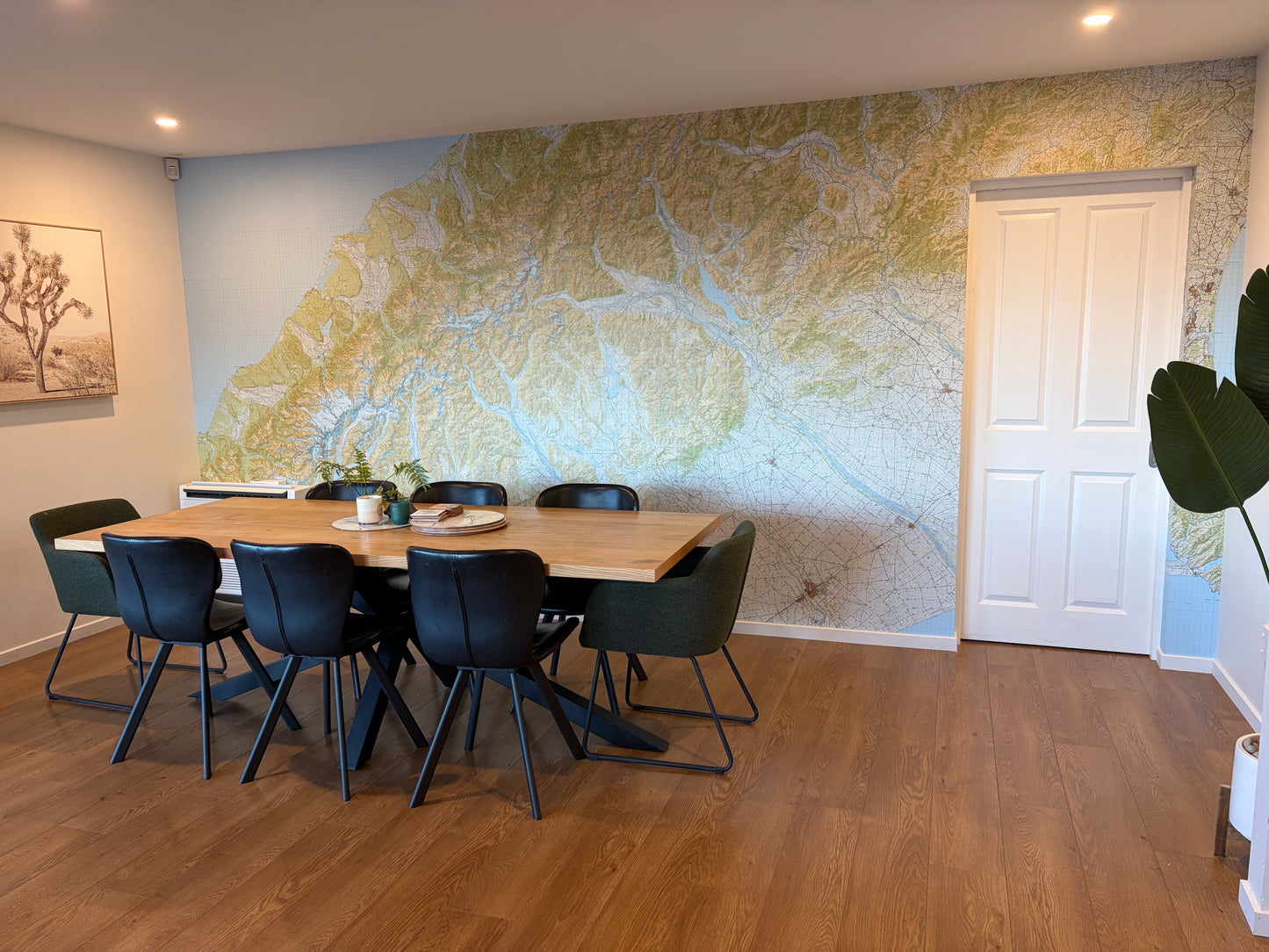 A modern dining room featuring a large wall with a topographic wallpaper map.