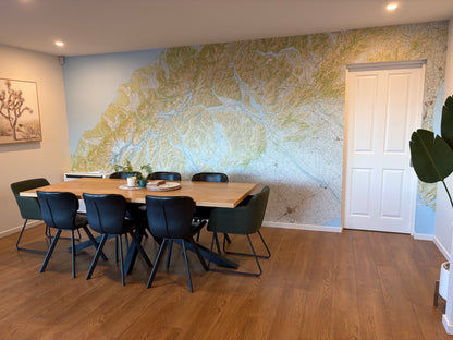 A modern dining room featuring a large wall with a topographic wallpaper map.