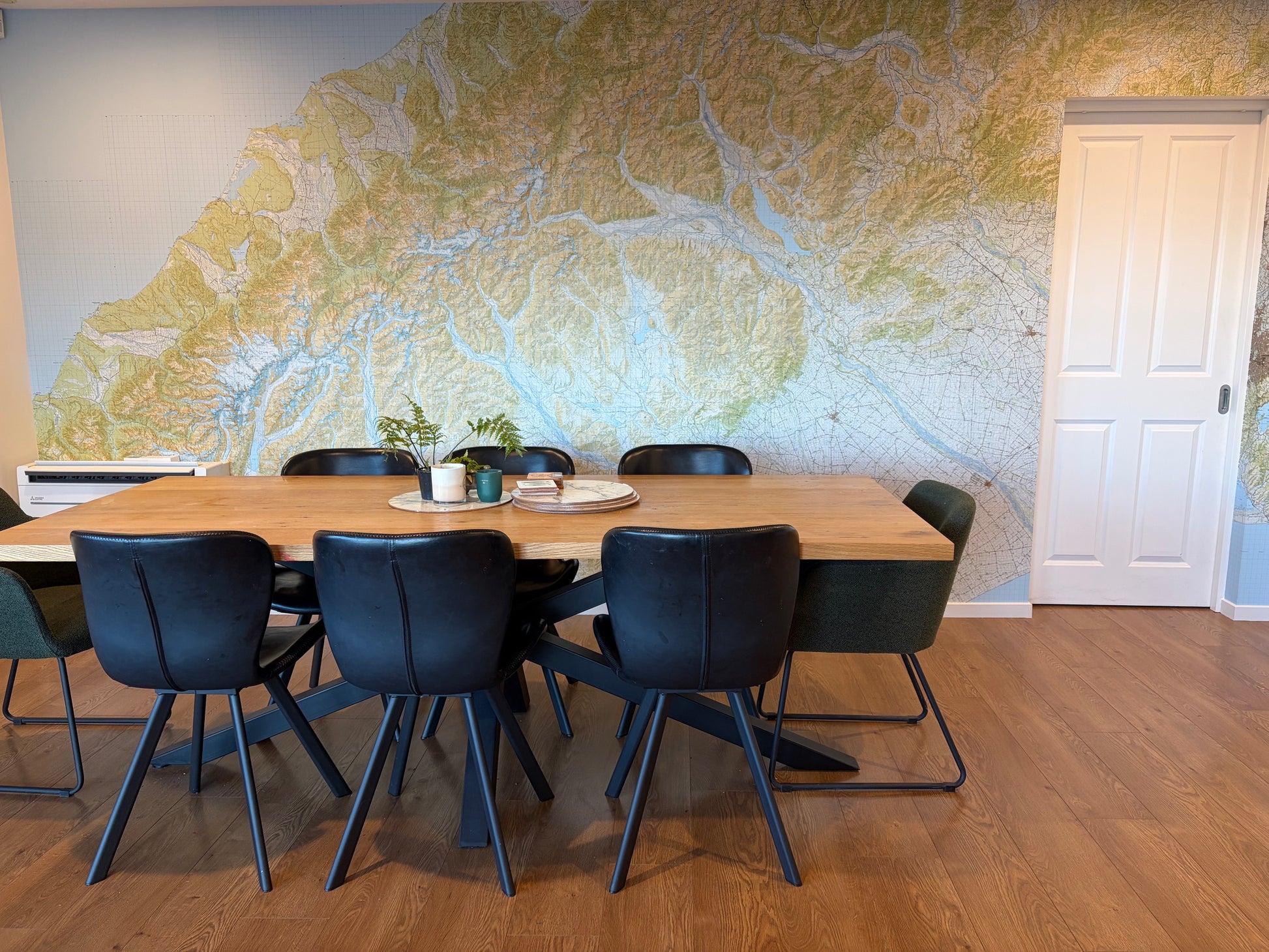 A modern dining room with a large topographical map wall mural.