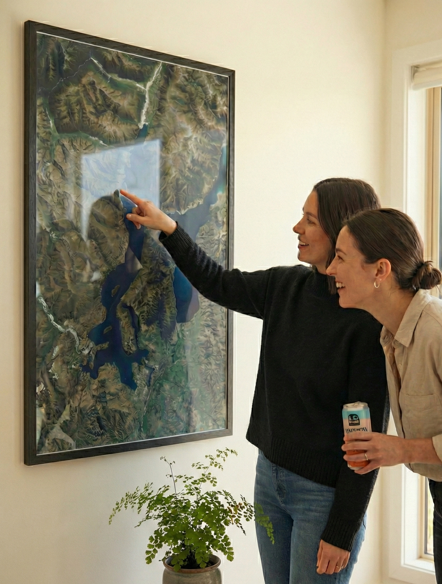 Two women looking at an aerial map of Wanaka on the wall.