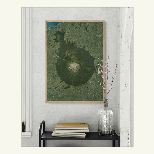Framed print of Taranaki on a wall with a vase and books below